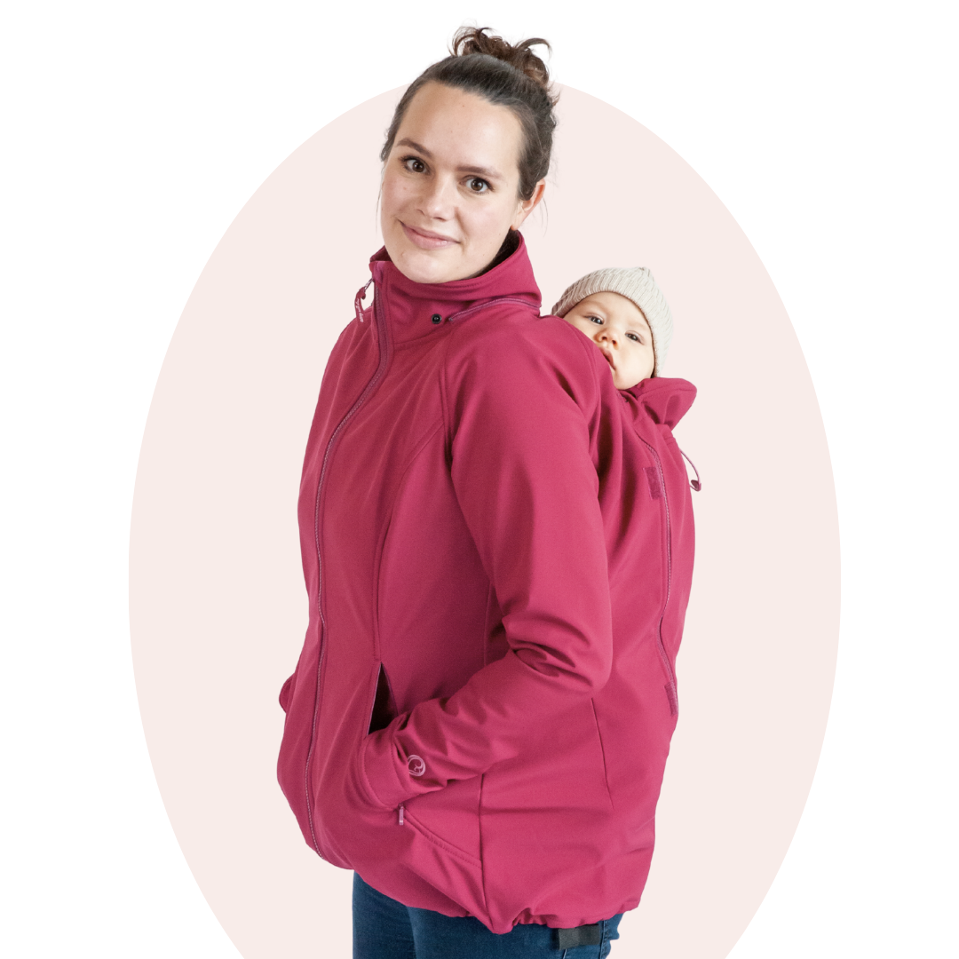 Mutter trägt Baby auf dem Rücken in pinker Softshell-Tragejacke, Studioaufnahme