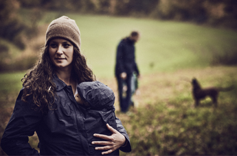 Mutter, die ihr Baby unter der Jacke trägt