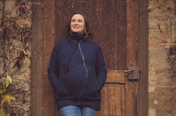 Pregnant woman stands for a wooden door