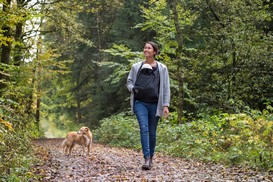 Mutter mit Baby und Hund mit Tragecover im Wald