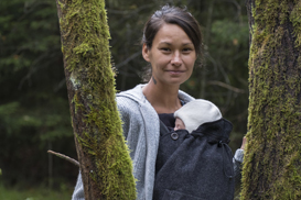 Mutter und Baby mit Tragecover im Wald